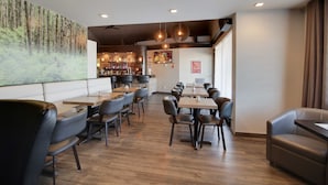 A restaurant with booths and tables, a bar area, and a large forest-themed mural on the wall.