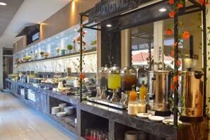 A buffet area with a variety of food items, beverage dispensers, and a push button sign.