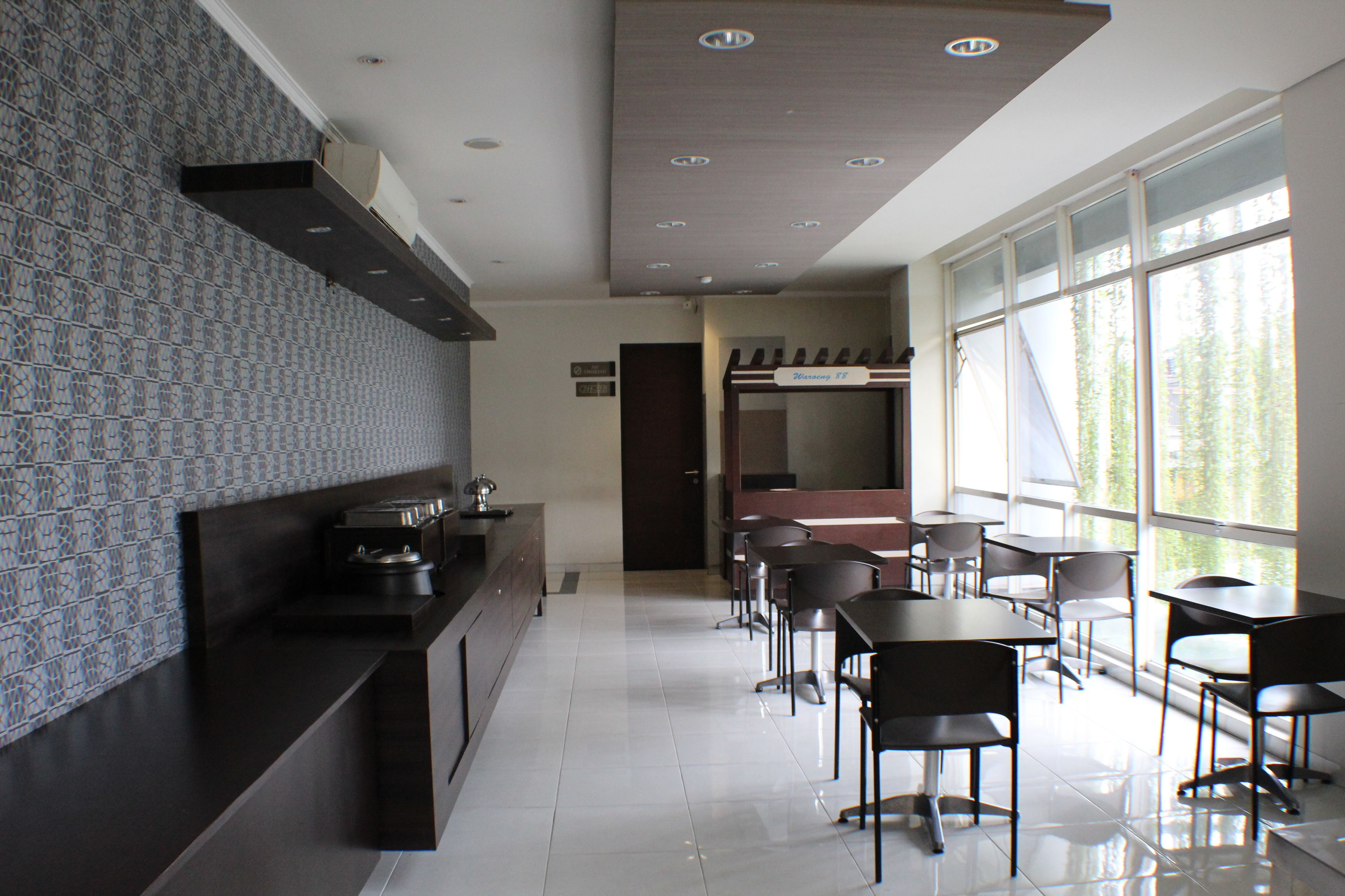 A modern kitchen with dark countertops, a patterned backsplash, and a dining area with black chairs and tables.