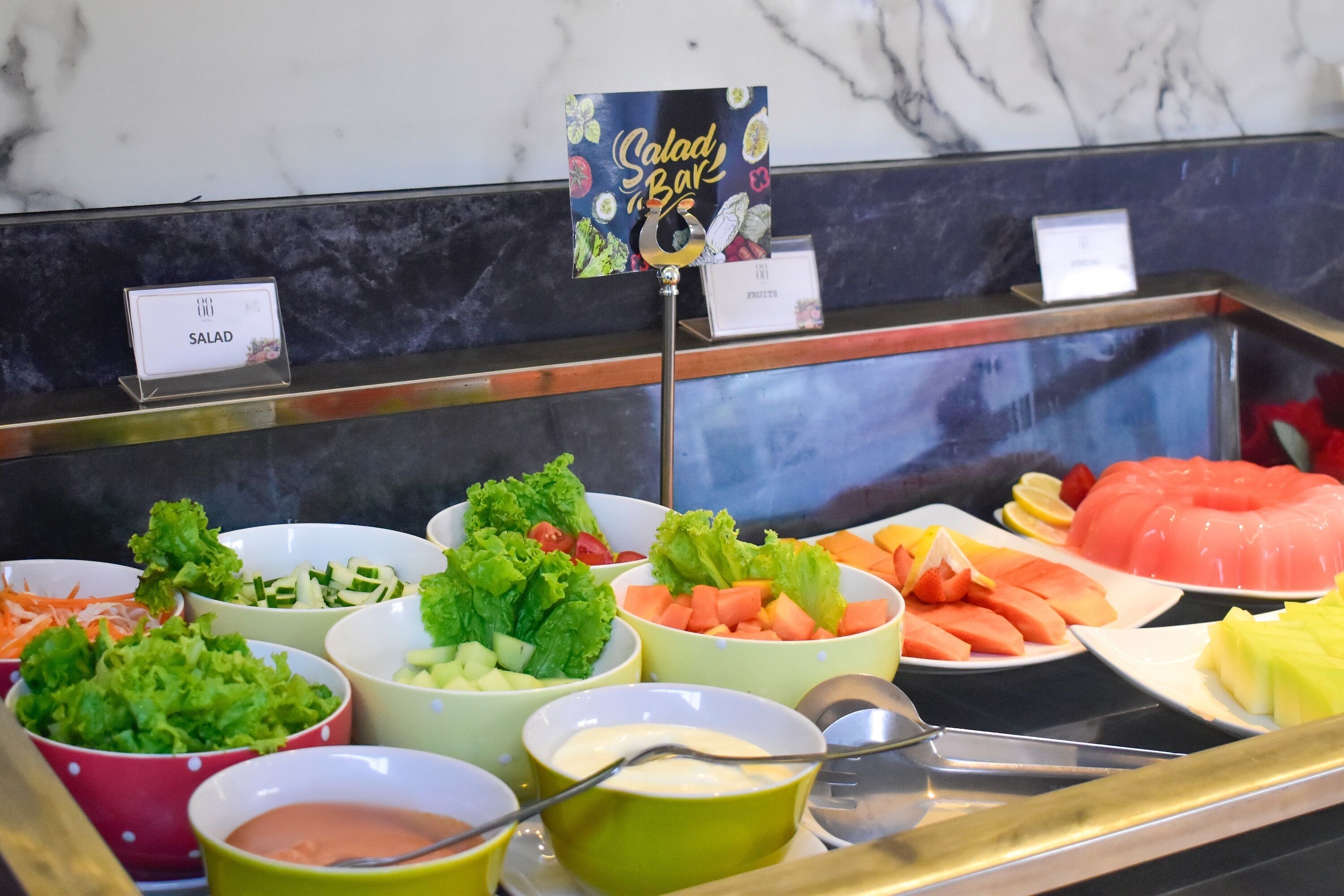 En salatbar med et udvalg af friske grøntsager og frugter.