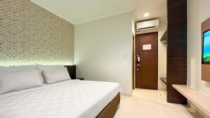 A hotel room with a bed, a wall-mounted TV, and an air conditioning unit. - Hotel 88 Embong Kenongo by WH (Surabaya)