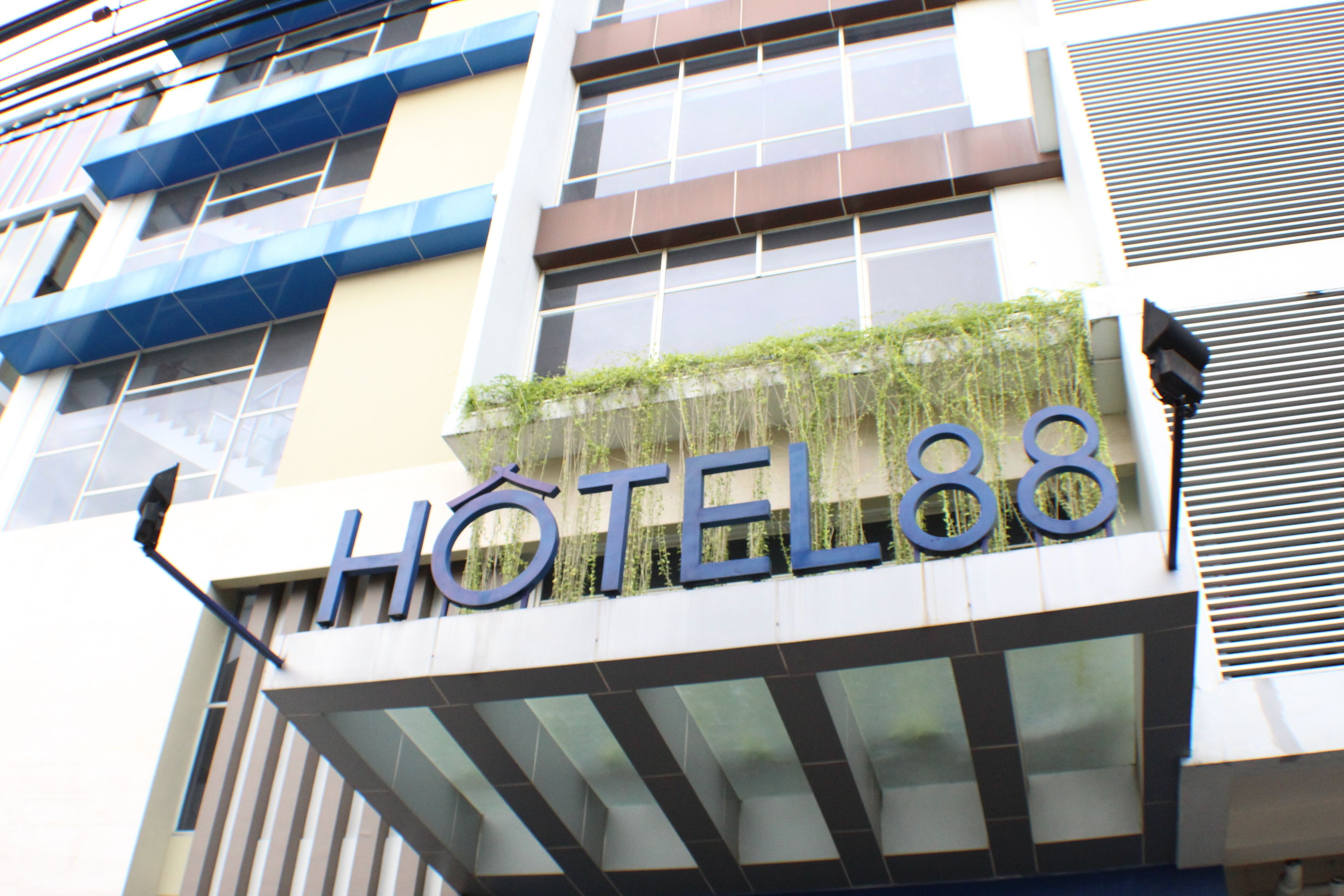 Un letrero de hotel con el nombre 'HOTEL88' y una fachada moderna con grandes ventanales y un diseño geométrico.