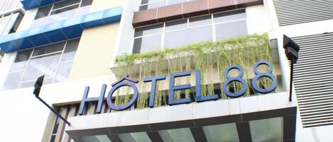 Un letrero de hotel con el nombre 'HOTEL88' y una fachada moderna con grandes ventanales y un diseño geométrico.
