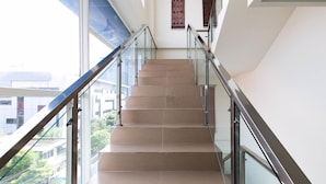A staircase with glass railings and beige steps, leading to an upper floor. - Hotel 88 Embong Kenongo by WH (Surabaya)