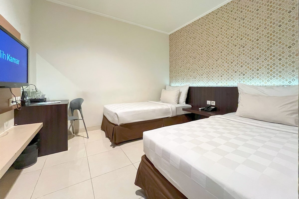 Una habitación de hotel con dos camas, un escritorio, una silla y un televisor.