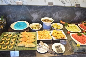 En buffet med et udvalg af mad, herunder croissanter, småkager, frugt og grøntsager.