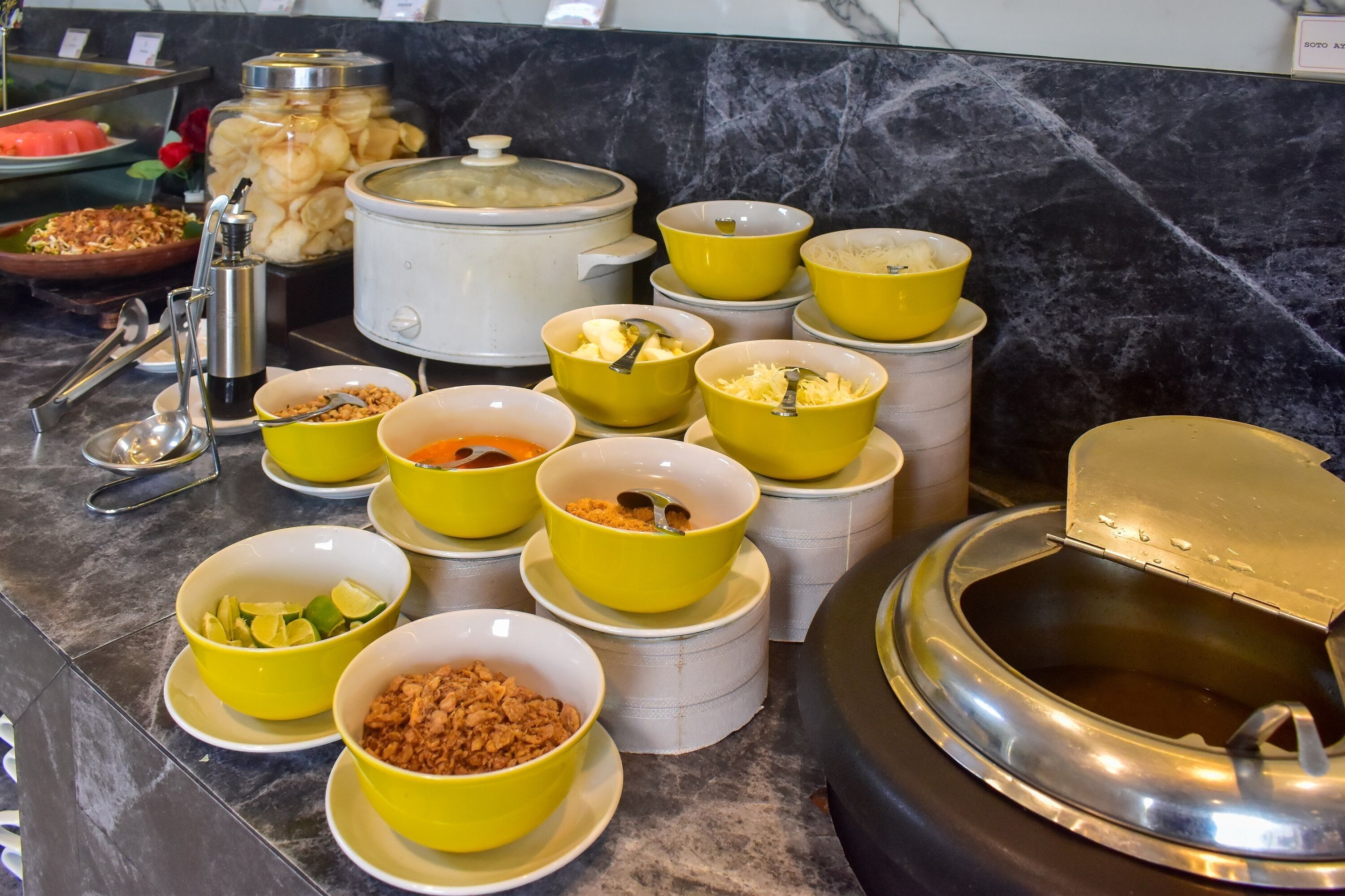 A buffet setup with various food items and containers.