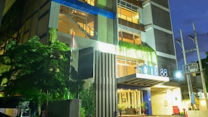 A modern hotel with multiple floors, large windows, and a well-lit entrance. - Hotel 88 Embong Kenongo by WH (Surabaya)