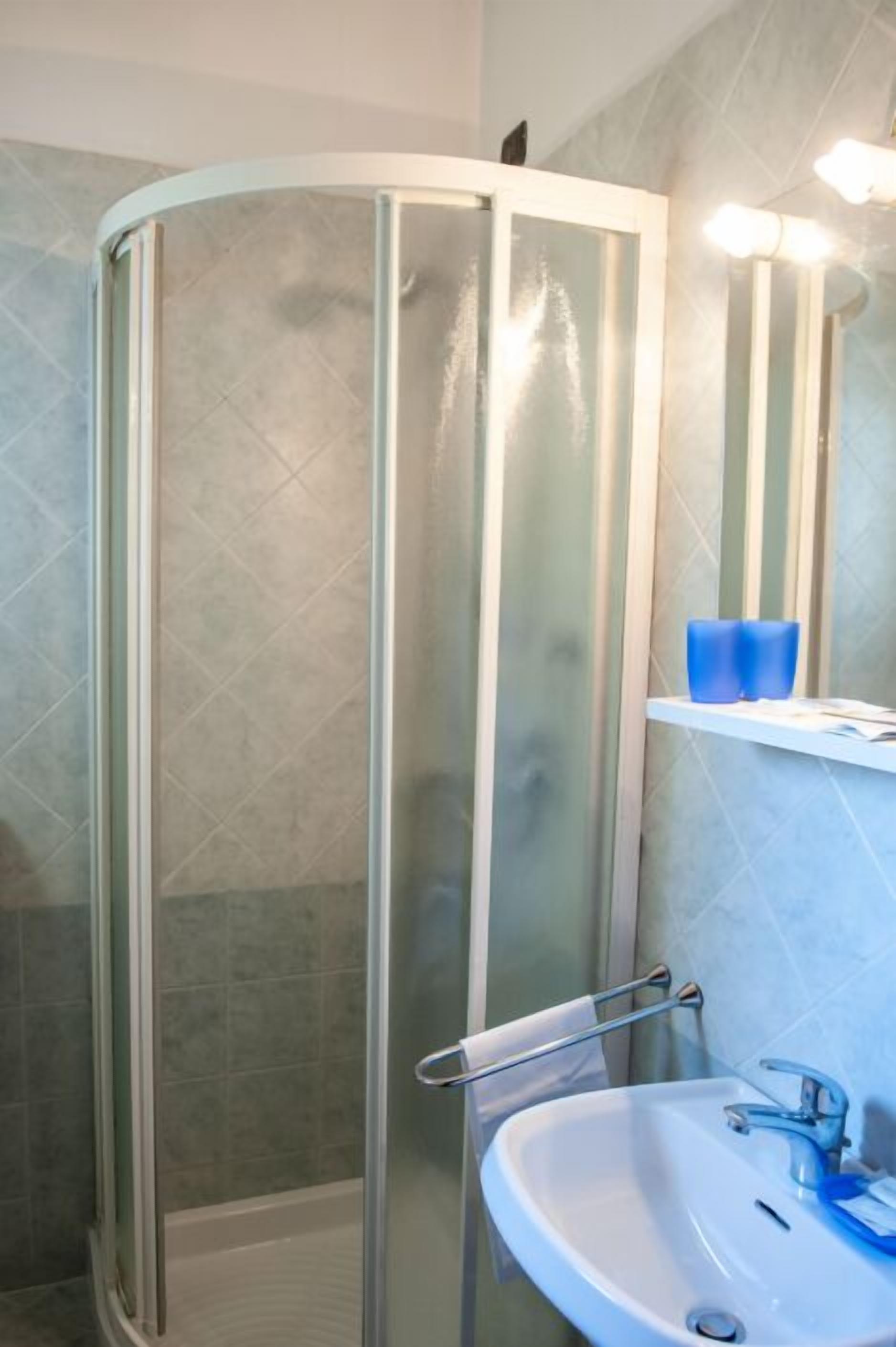 Un bagno con cabina doccia in vetro, un lavabo con specchio e un porta asciugamani.