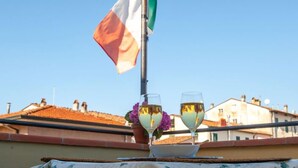 Two glasses of white wine on a table with a flag in the background. - Hotel Melecchi (Lucca)