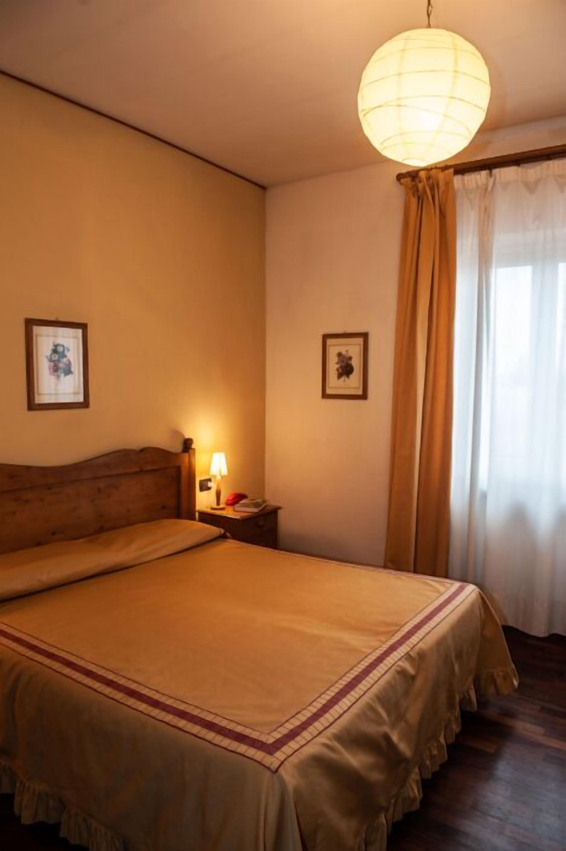Ein Schlafzimmer mit einem großen Bett, einem Nachttisch mit Lampe und zwei gerahmten Bildern an der Wand.