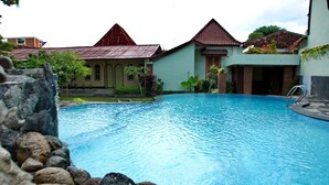A swimming pool surrounded by stone walls and houses with red roofs.