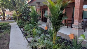 A hotel courtyard with a paved walkway, surrounded by various potted plants and trees.