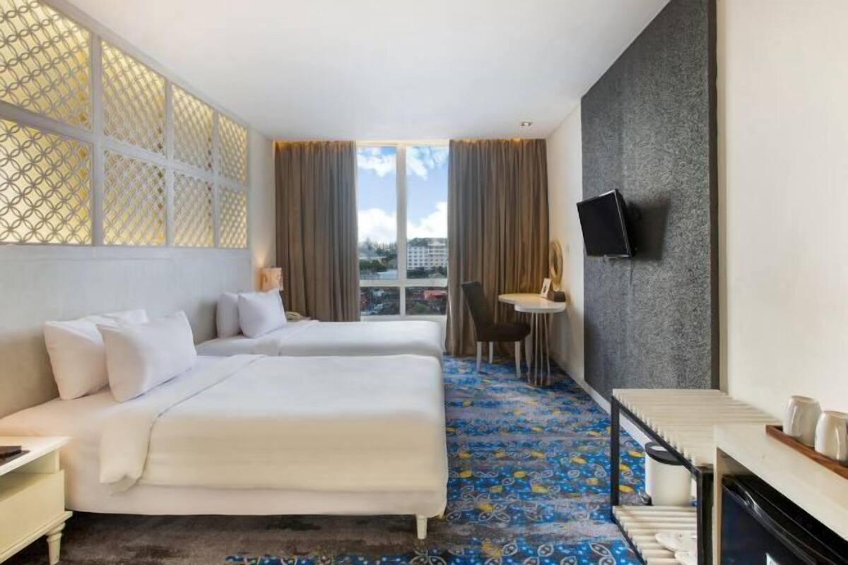 Une chambre d’hôtel avec deux lits, une télévision, une petite table et une vue sur la ville.