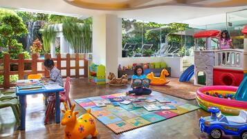 Children can play and learn in this vibrant play area, featuring a train set, ride-on toy car, and cozy reading nook.