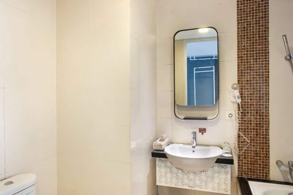 Une salle de bain avec un lavabo blanc, un miroir et un espace douche.