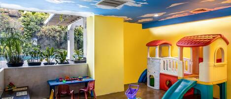 A children's playroom with a colorful playhouse, a slide, and educational toys on the table.