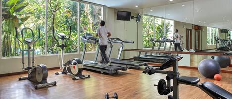 A gym with treadmills, exercise bikes, and free weights.