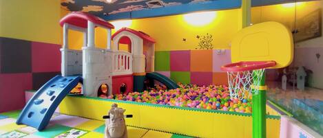 A play area with a ball pit, a slide, and a small basketball hoop.