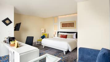 A hotel room with a bed, a desk, a chair, and a sofa.