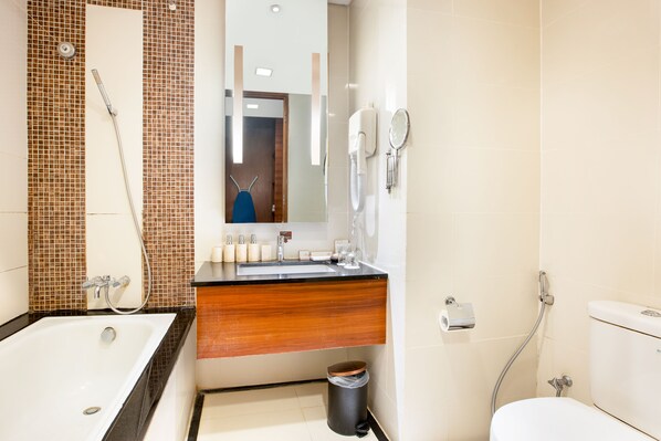 A modern bathroom with a bathtub, a sink with a mirror, and a toilet.