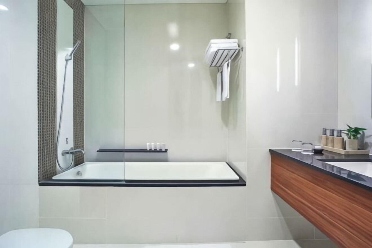 Un bagno moderno con cabina doccia in vetro, lavabo bianco e mobile vanità in legno.