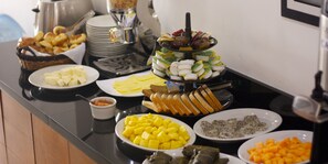 A buffet with various food items including bread, cheese, fruits, and condiments.