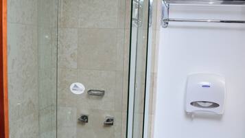 Un baño con cabina de ducha de vidrio, inodoro y secador de manos.
