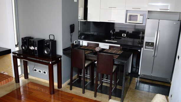 Una cocina compacta con comedor, microondas integrado y refrigerador.