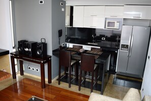 A compact kitchen with a dining area, a built-in microwave, and a refrigerator. - Prisma Suites Chicó 94 (Bogotá)