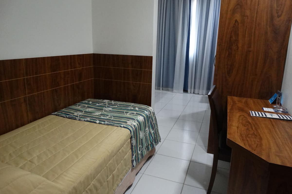 A room with a bed, a wooden desk, and a chair.