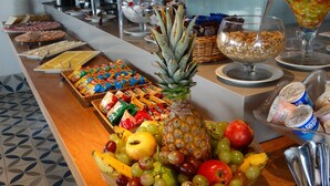 A buffet with various food items including fruits, sandwiches, and a salad. - Praia Linda (Rio de Janeiro)
