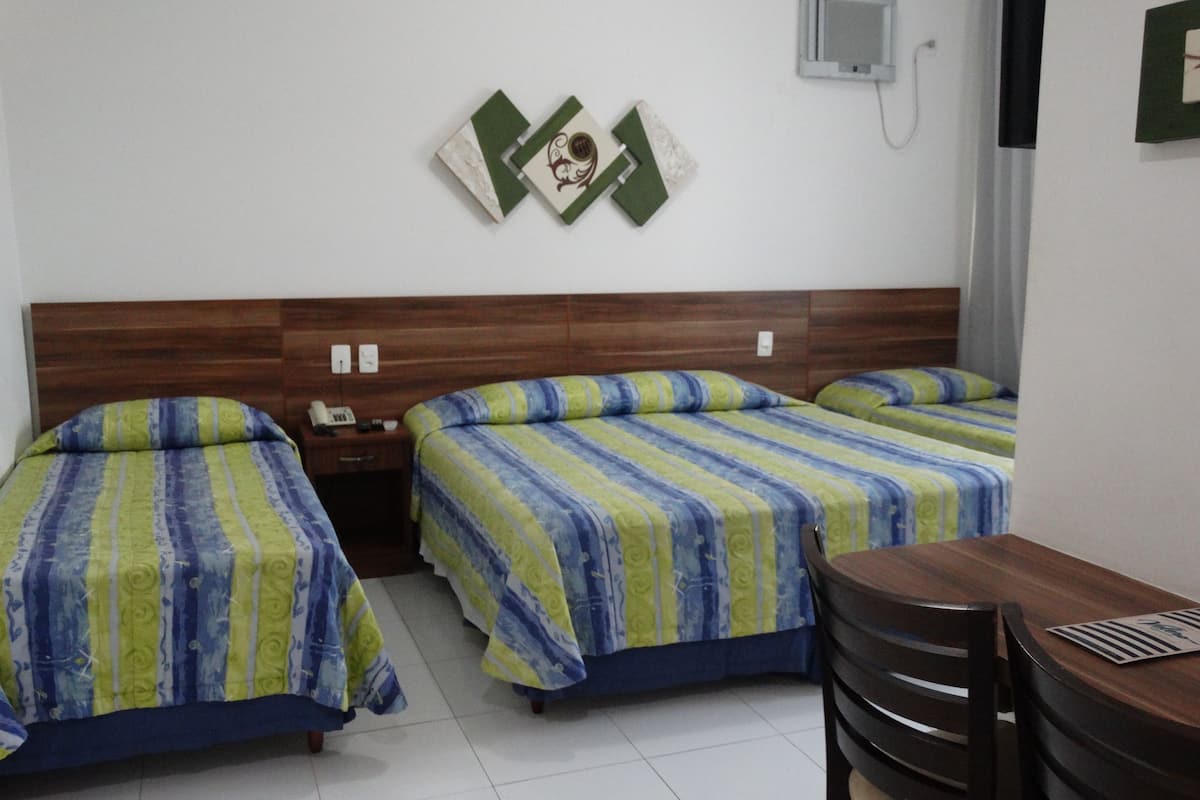 A hotel room with two beds, a wooden headboard, a small table, and a wall-mounted phone.