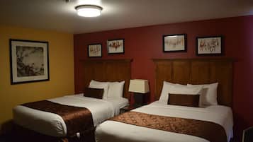 A hotel room with two beds, wooden headboards, and a red accent wall.