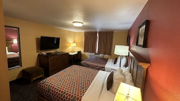 Une chambre d’hôtel avec deux lits, un bureau, une télévision et une fenêtre avec des rideaux.