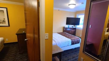 A hotel room with a bed, a desk, a dresser, a television, and a window.