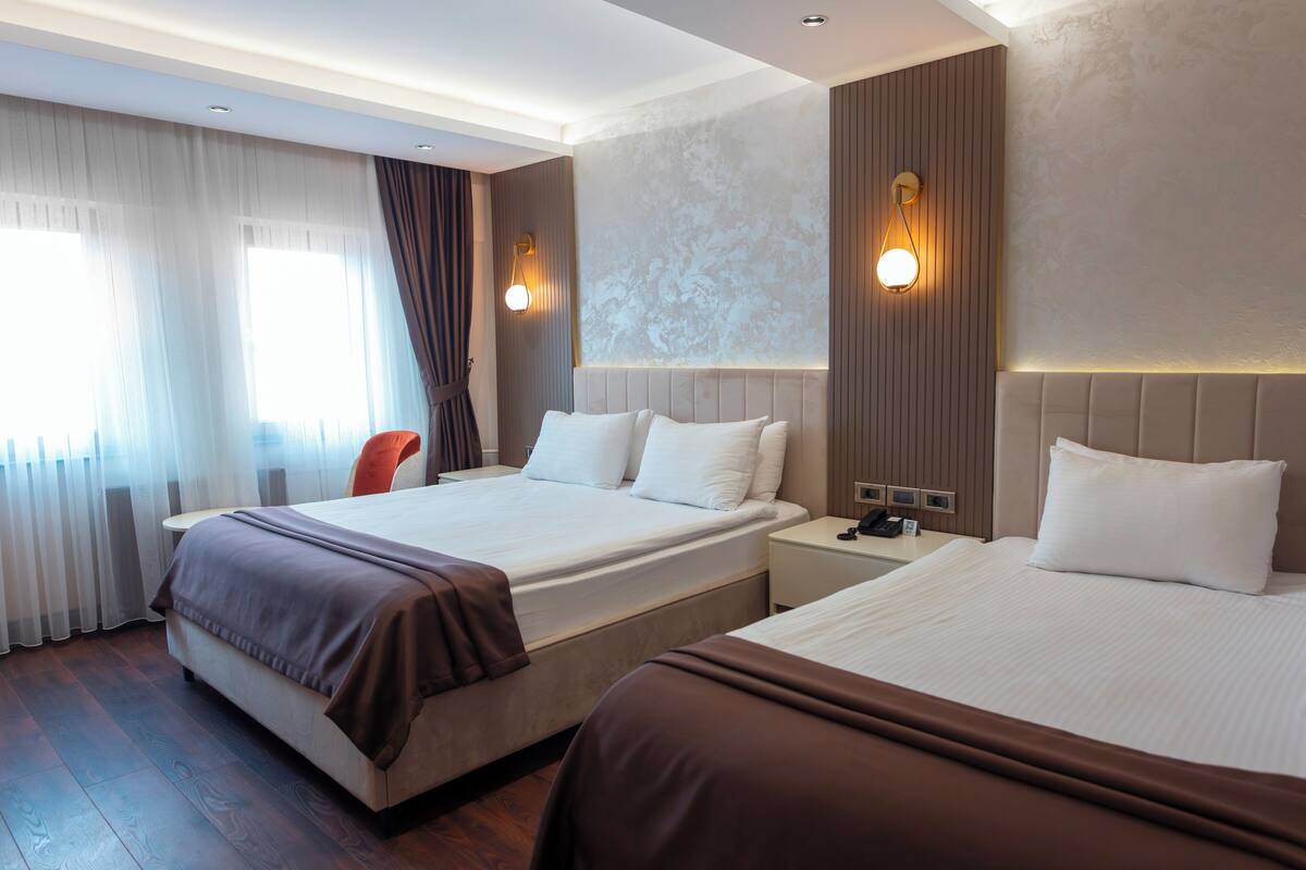 Ein Hotelzimmer mit zwei Betten, einem Schreibtisch, einem Stuhl und einem Fenster mit Vorhängen.