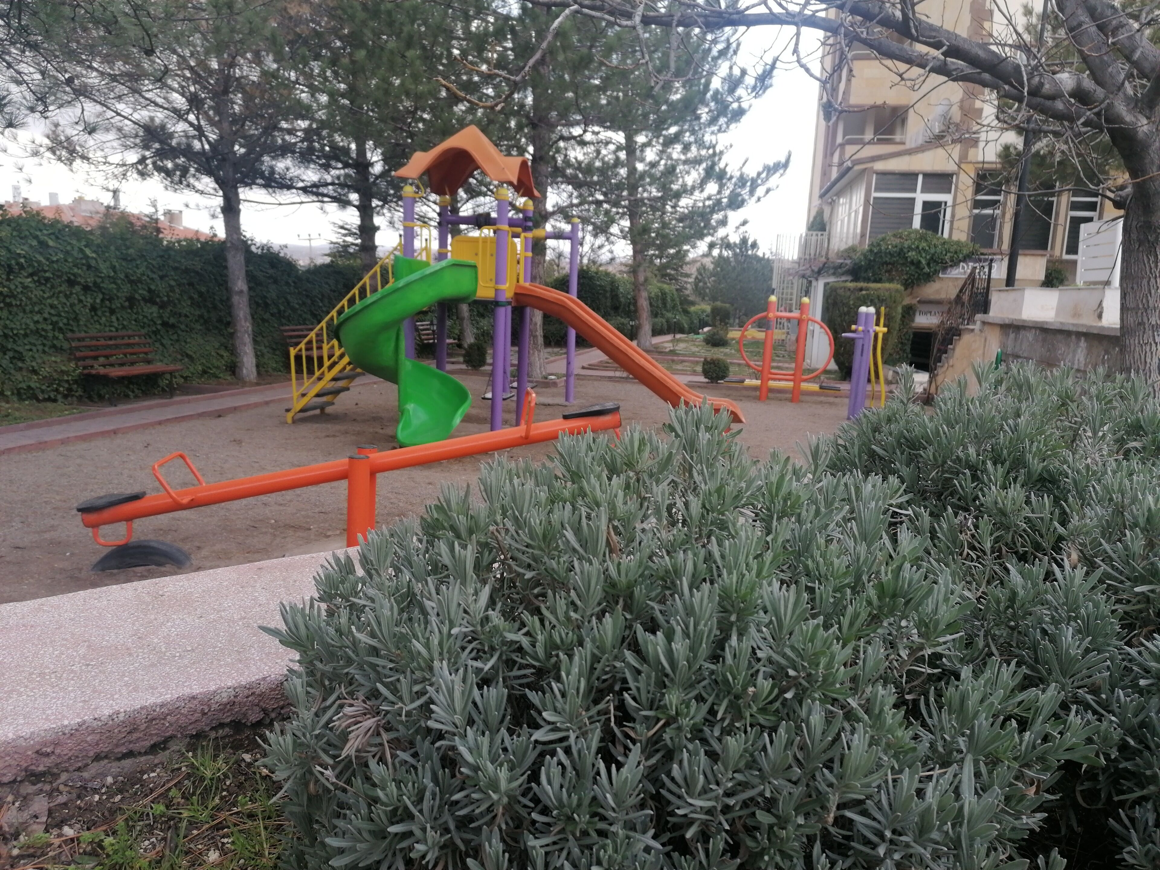 Un parque infantil con tobogán, estructura para escalar y columpios.