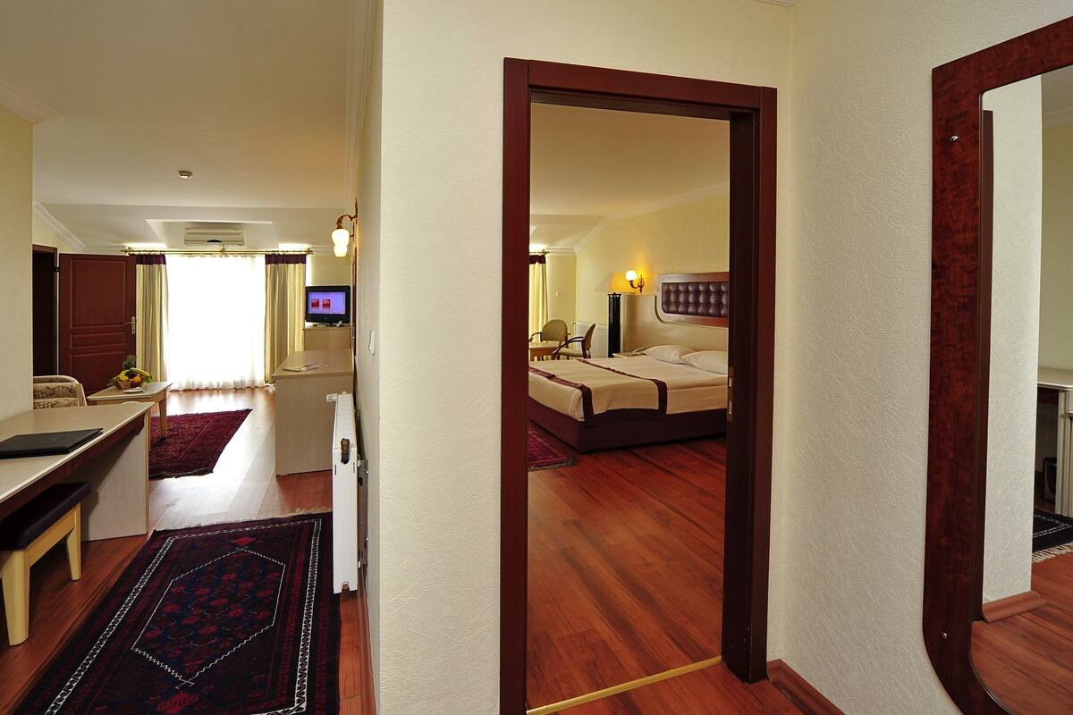 Ein Hotelzimmer mit Bett, Nachttisch, Stuhl und Schreibtisch mit Computer.