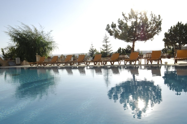 Una piscina techada, una piscina al aire libre, sombrillas