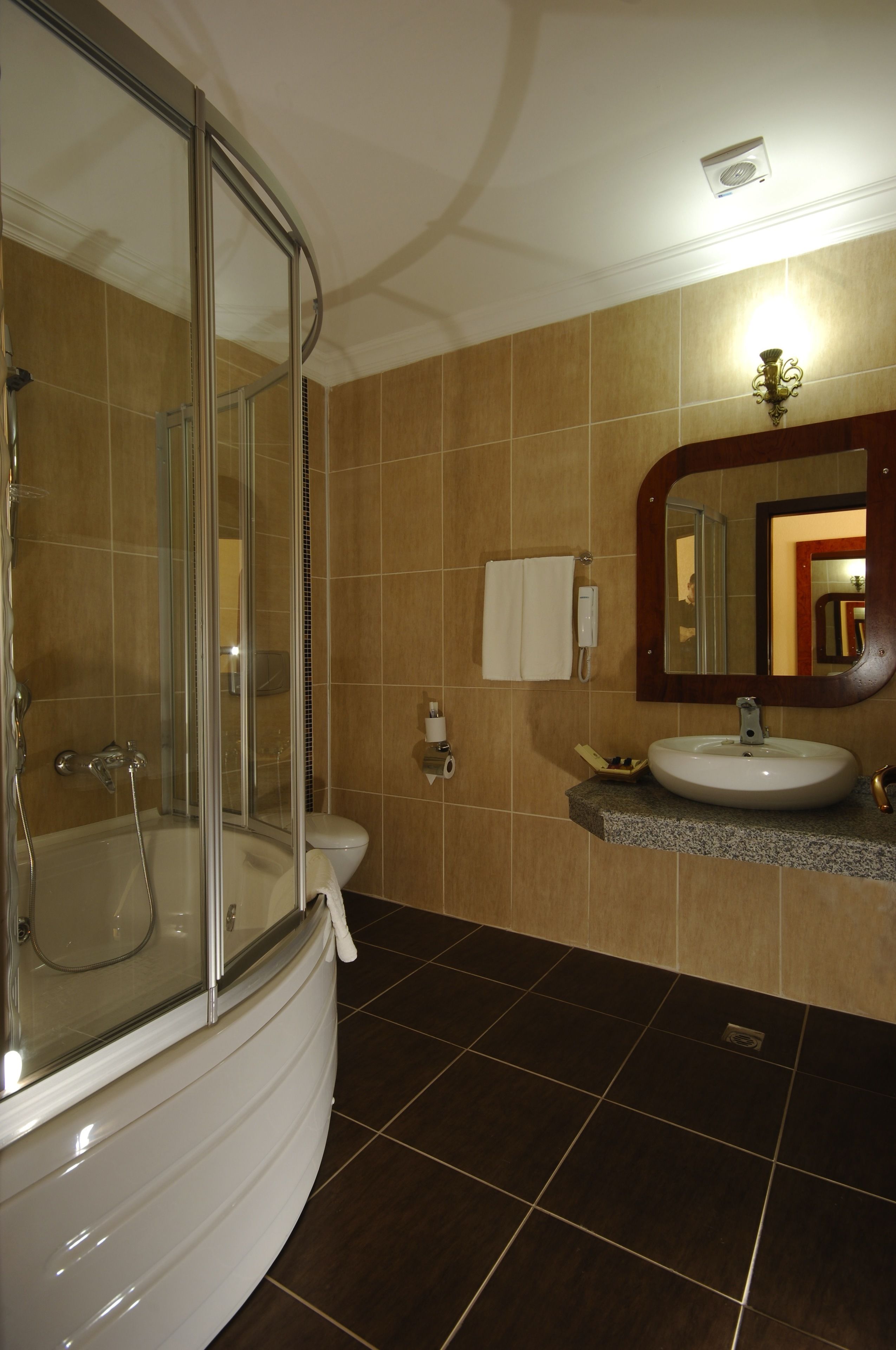 A bathroom with a glass-enclosed shower, a sink, and a mirror.
