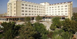 Un hotel grande con varios pisos, un patio central con asientos al aire libre y una piscina.