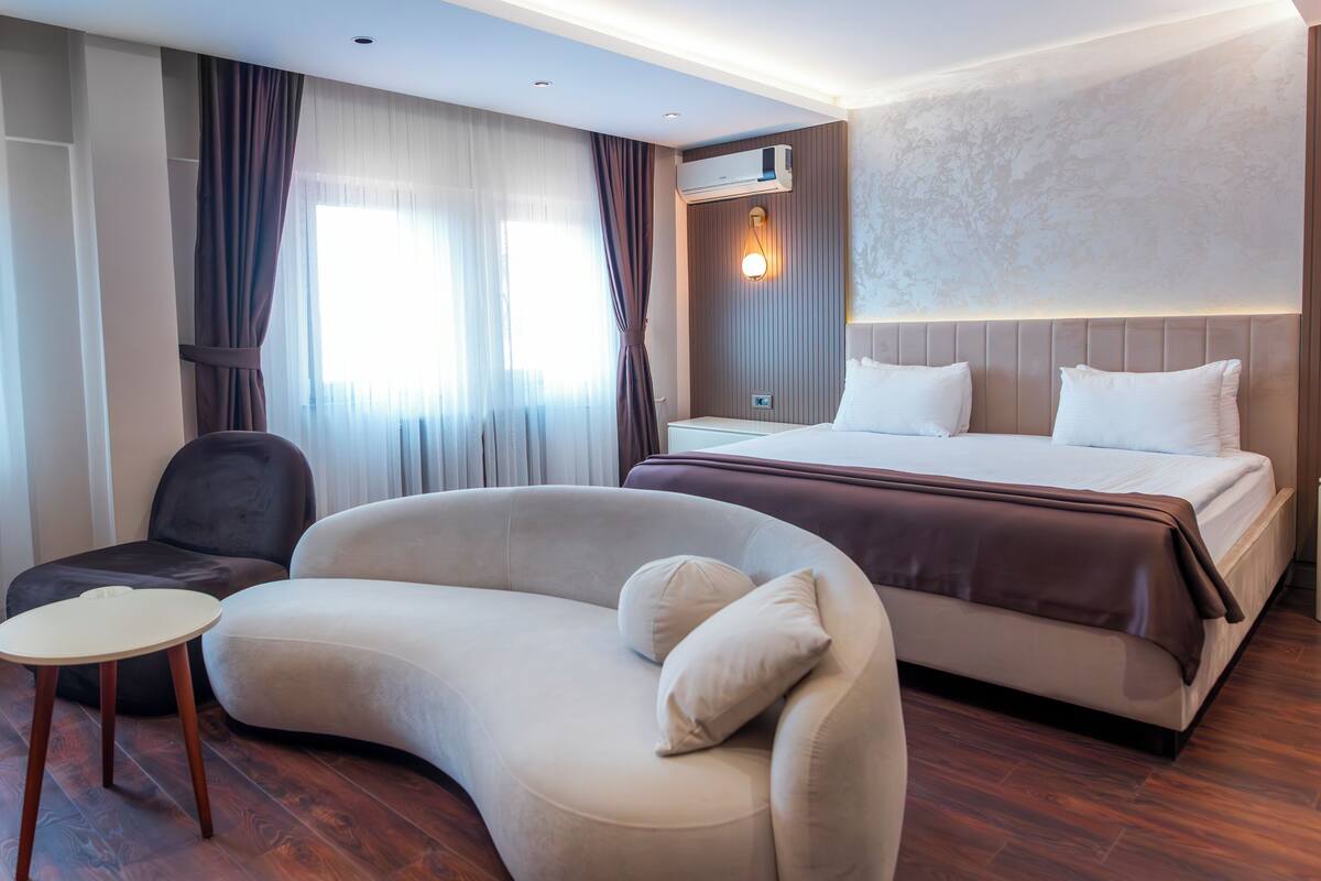 Ein Hotelzimmer mit einem großen Bett, einer gebogenen Couch, einem kleinen Tisch und einem Sessel.