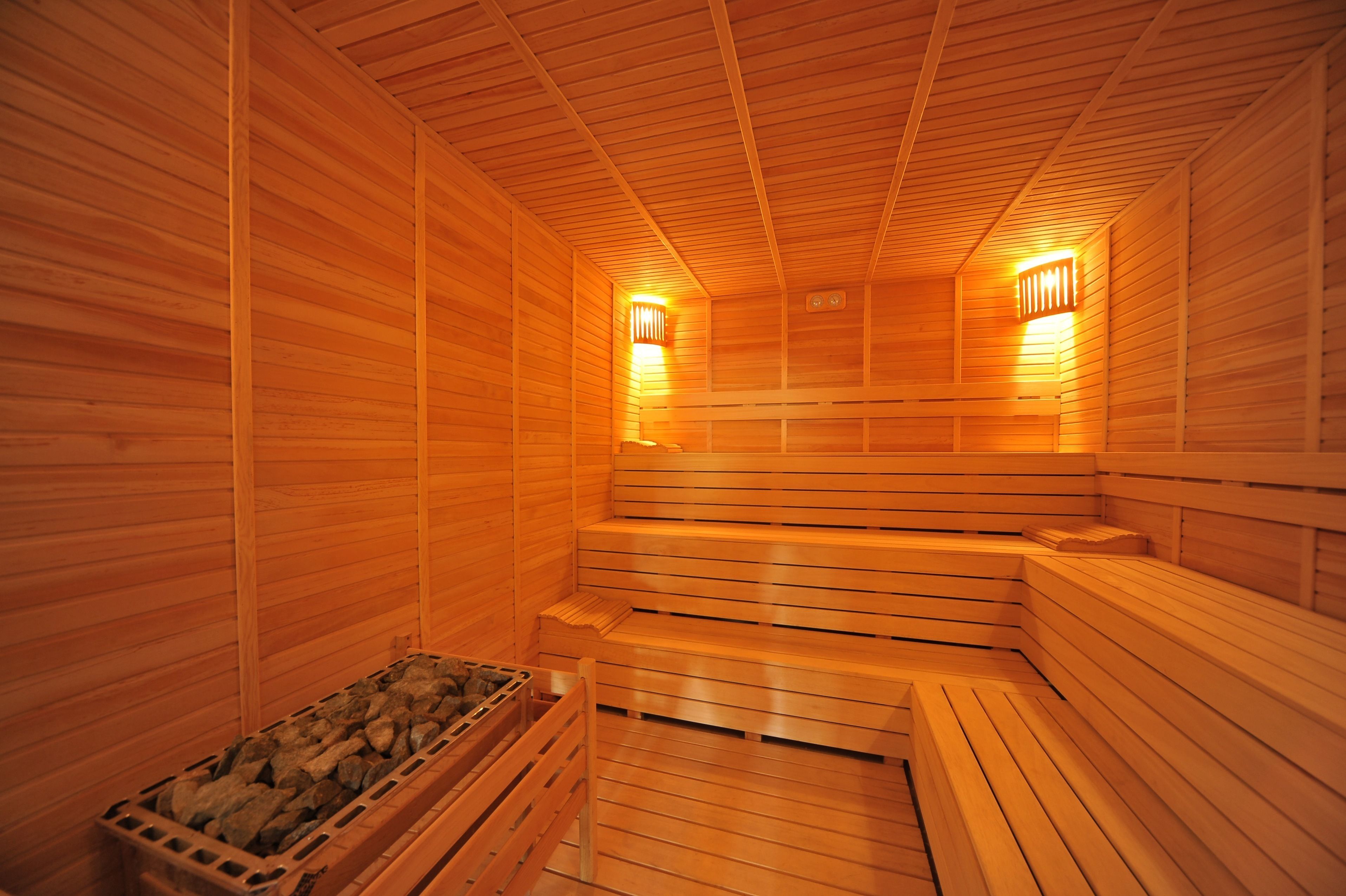 A wooden sauna with benches and a stone-filled container.