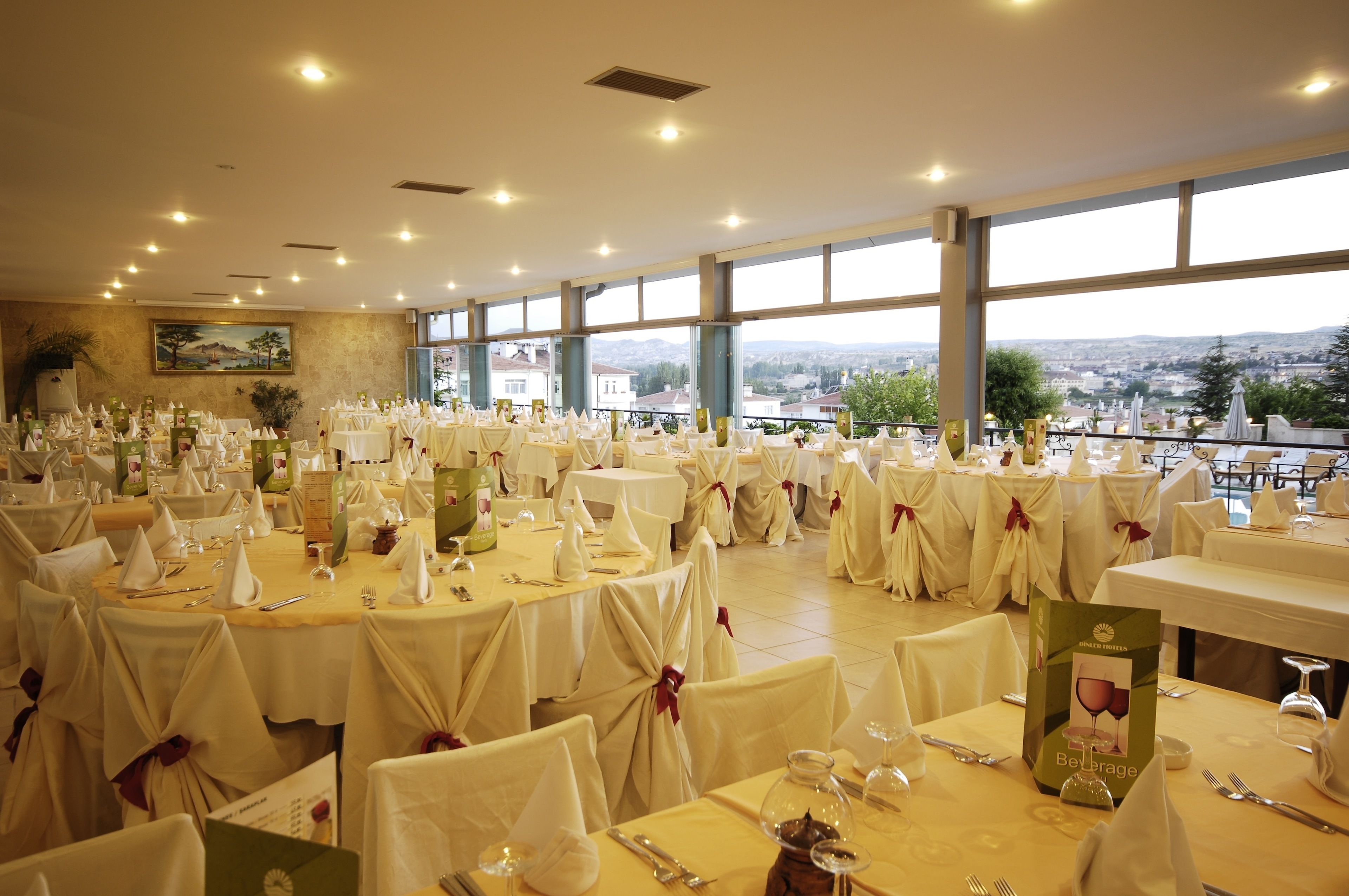 Un salón de banquetes con mesas redondas cubiertas con manteles blancos y sillas, preparado para un evento formal.