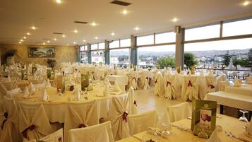 Un salón de banquetes con mesas redondas cubiertas con manteles blancos y sillas, preparado para un evento formal.