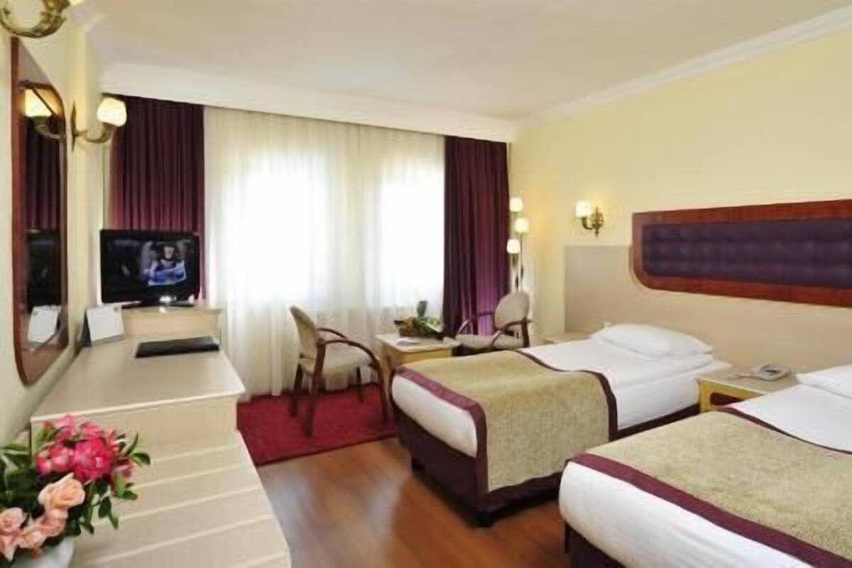 Ein Hotelzimmer mit zwei Betten, einem Fernseher, einem Schreibtisch und einem Stuhl.