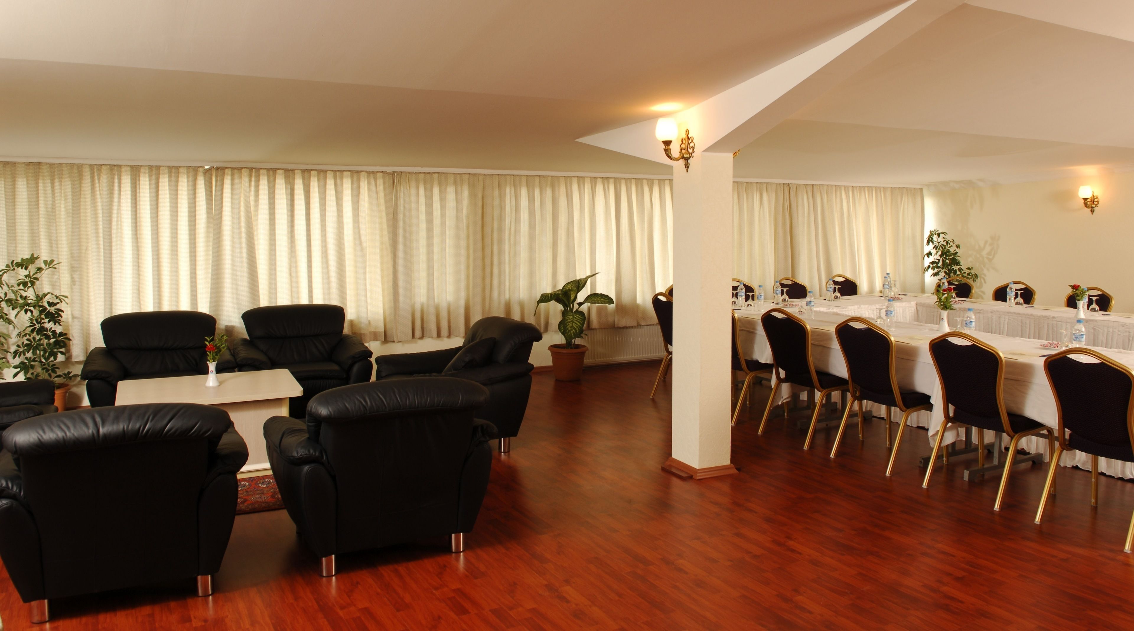 A conference room with a long table, black leather chairs, and a potted plant.