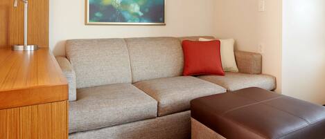 A modern living room with a sofa, ottoman, and a wooden side table.