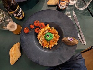 Une assiette de nourriture, une bouteille de bière et un verre de bière sur une table.